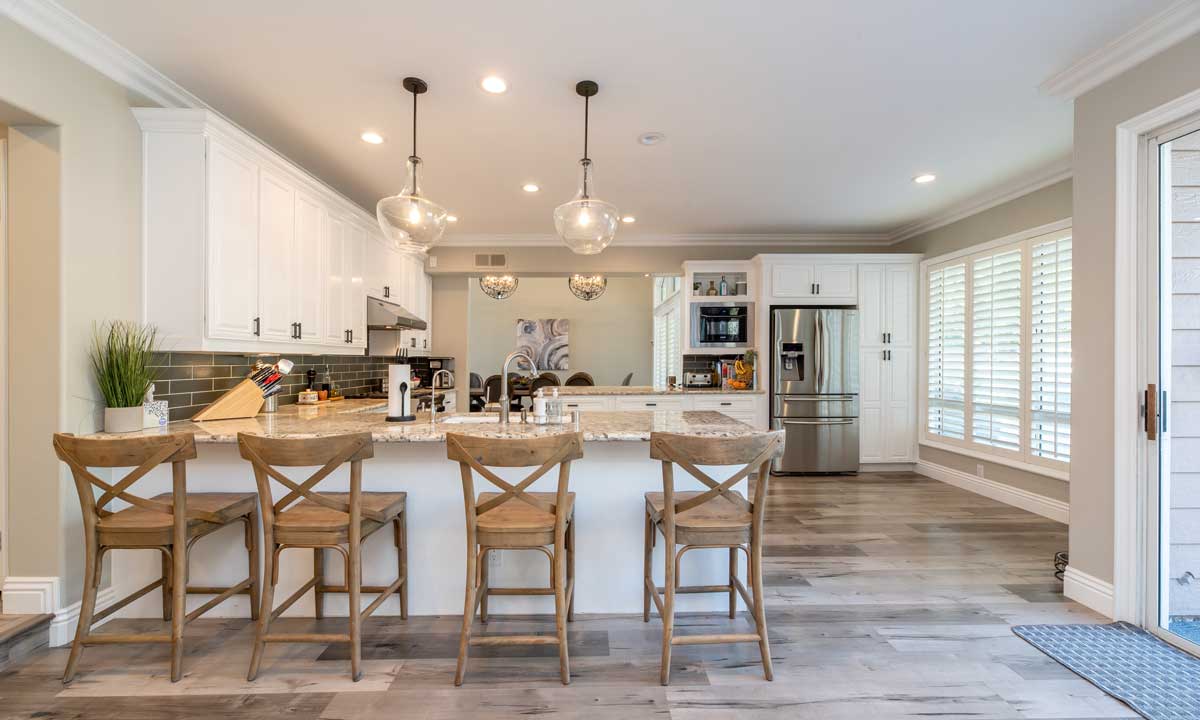 inside of a kitchen with droplights and white cabinets, wood floor.